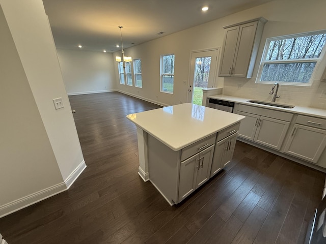 kitchen featuring dishwasher, a kitchen island, dark hardwood / wood-style flooring, sink, and hanging light fixtures