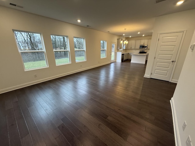 unfurnished living room featuring an inviting chandelier and dark hardwood / wood-style floors