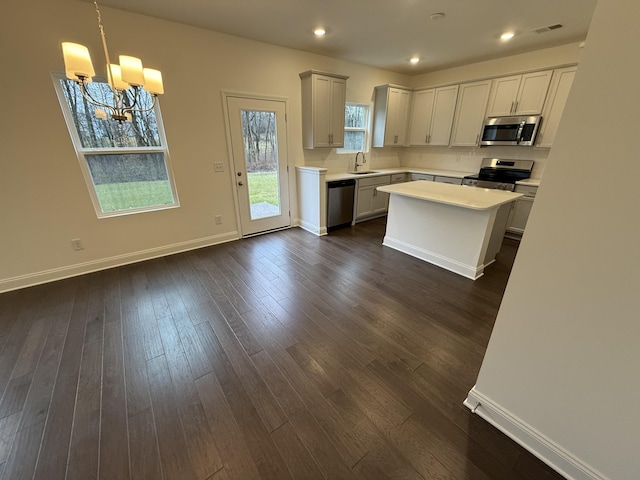 kitchen with a center island, pendant lighting, sink, stainless steel appliances, and a chandelier