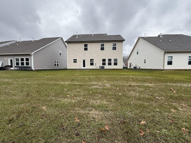 back of house with cooling unit and a lawn