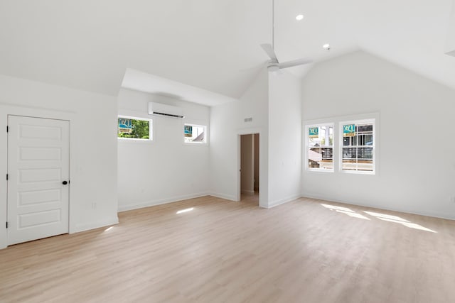 interior space with light hardwood / wood-style floors, a wall unit AC, multiple windows, and ceiling fan