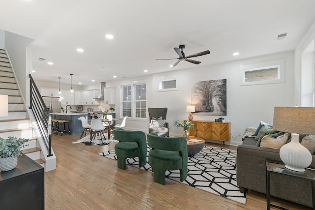 living room featuring light hardwood / wood-style flooring, ceiling fan, and sink