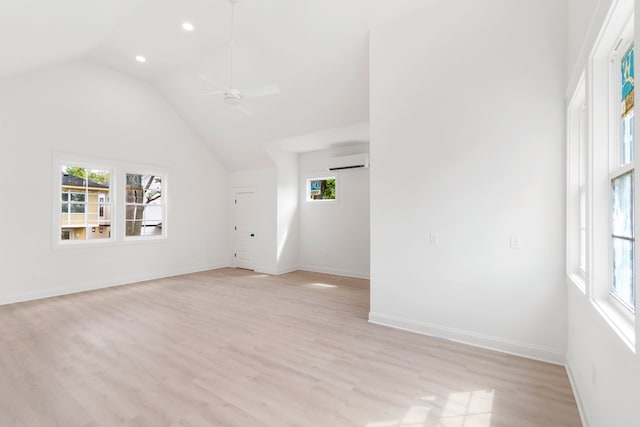 interior space with a wall mounted AC, light wood-type flooring, ceiling fan, and vaulted ceiling