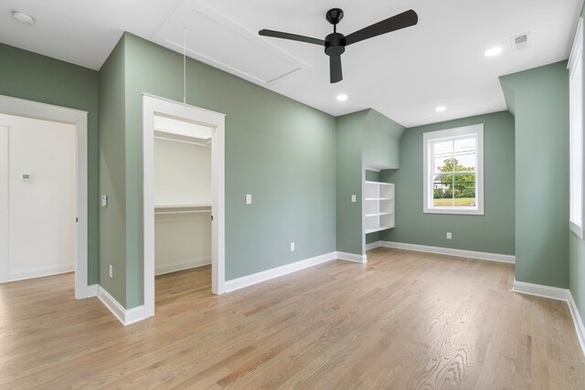 unfurnished bedroom featuring a closet, light wood-type flooring, a walk in closet, and ceiling fan