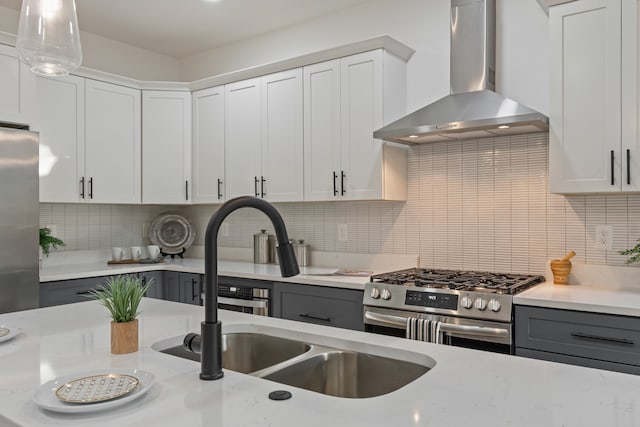 kitchen featuring white cabinets, wall chimney range hood, and appliances with stainless steel finishes