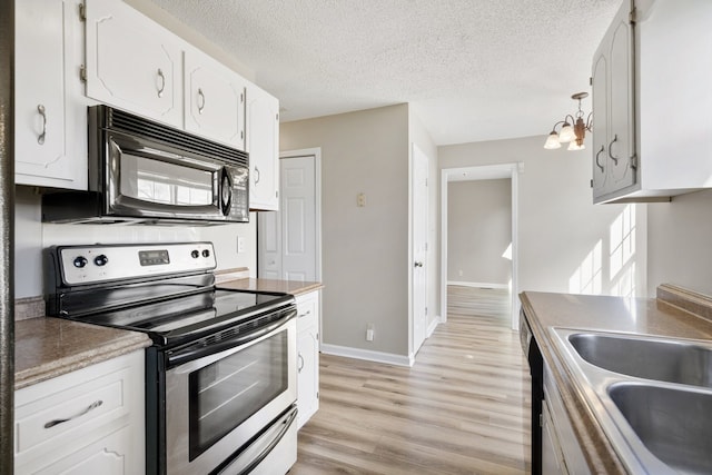 kitchen featuring white cabinets, a textured ceiling, appliances with stainless steel finishes, a notable chandelier, and light hardwood / wood-style floors