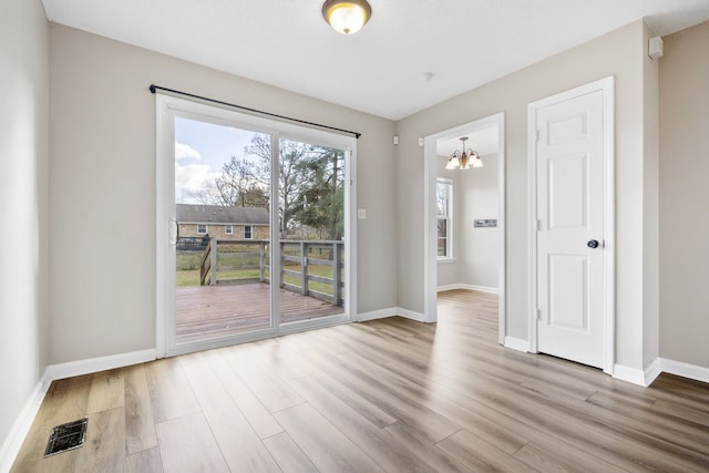 unfurnished room featuring light hardwood / wood-style flooring and a notable chandelier