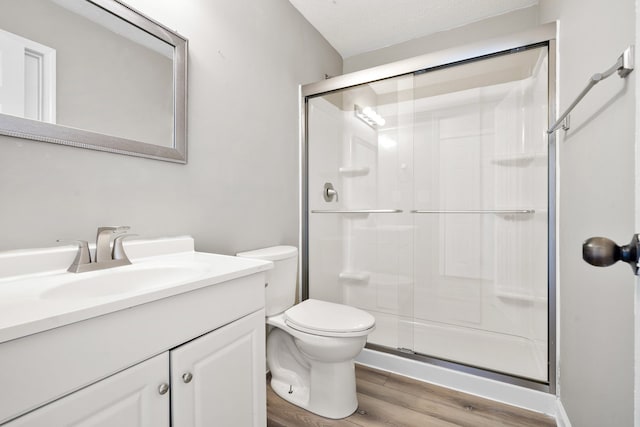 bathroom featuring hardwood / wood-style floors, vanity, toilet, walk in shower, and a textured ceiling