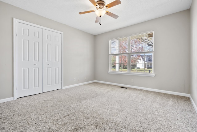 unfurnished bedroom with ceiling fan, a closet, and carpet floors