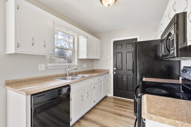 kitchen with a textured ceiling, sink, black appliances, light hardwood / wood-style flooring, and white cabinets