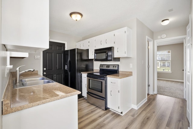 kitchen with light wood-type flooring, a textured ceiling, sink, black appliances, and white cabinets