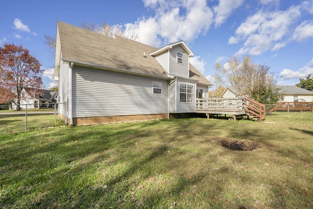 rear view of house featuring a wooden deck and a yard