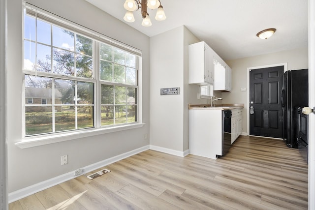 kitchen featuring black appliances, sink, light hardwood / wood-style flooring, a notable chandelier, and white cabinetry