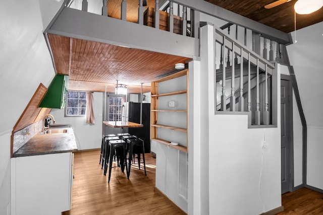 kitchen with wooden ceiling, black refrigerator, sink, ceiling fan, and light hardwood / wood-style floors