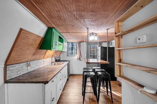 kitchen with sink, light hardwood / wood-style flooring, backsplash, black refrigerator, and white cabinets