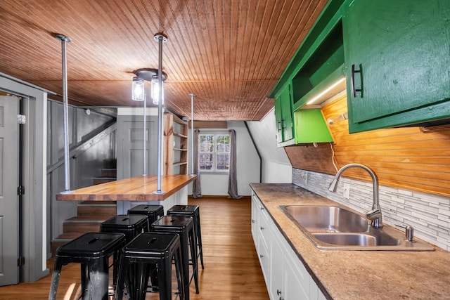 kitchen with wood counters, green cabinets, sink, light wood-type flooring, and white cabinetry