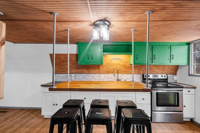 kitchen with stainless steel range with electric stovetop, wood counters, green cabinets, and a breakfast bar