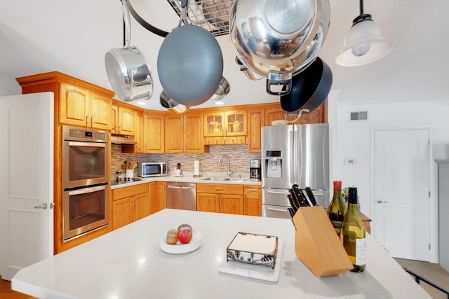 kitchen with stainless steel appliances, sink, decorative light fixtures, and tasteful backsplash