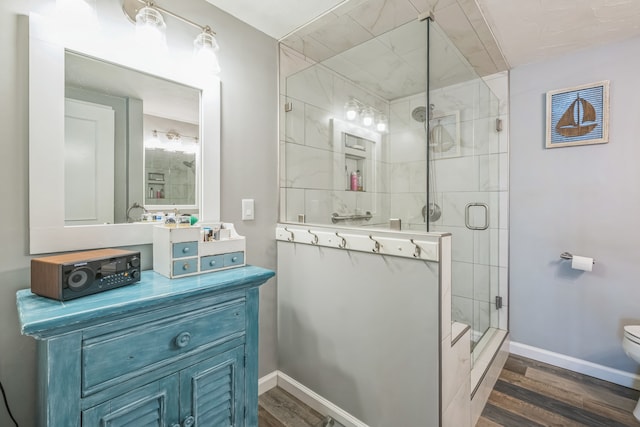 bathroom featuring toilet, vanity, wood-type flooring, and a shower with shower door