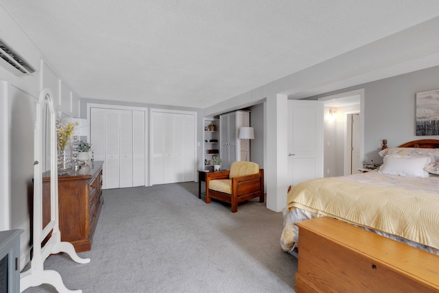 bedroom with multiple closets, carpet floors, and a textured ceiling