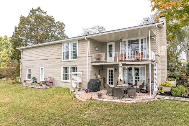 rear view of property featuring a balcony, a yard, and a patio area