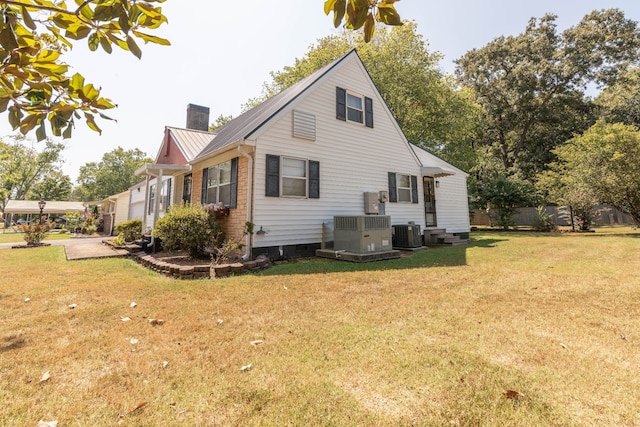 back of property with central air condition unit and a lawn