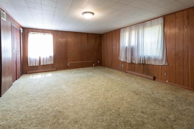 unfurnished room with wood walls and baseboard heating