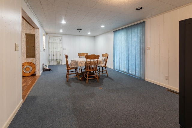 carpeted dining area featuring wooden walls