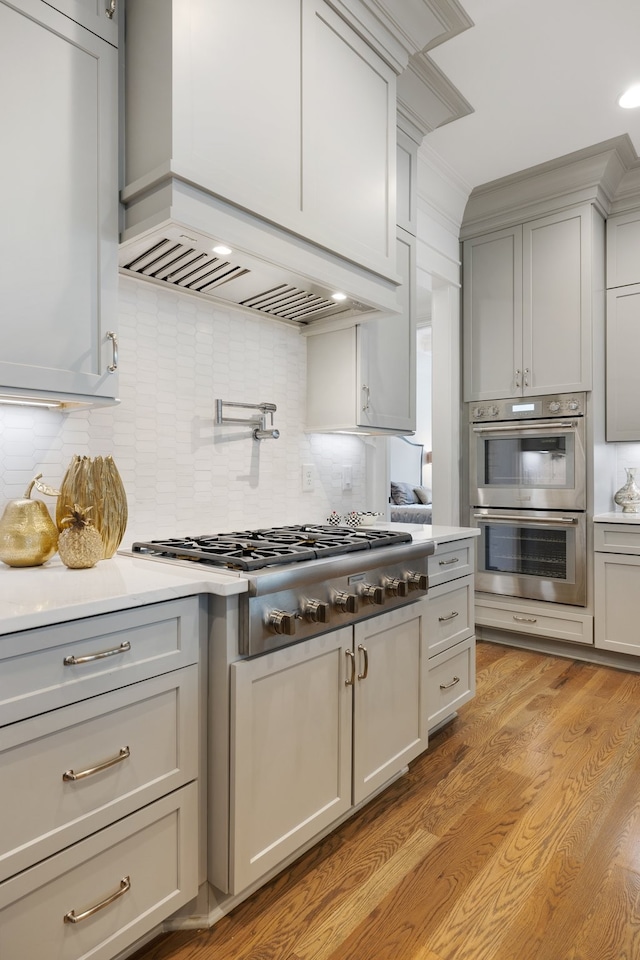 kitchen featuring tasteful backsplash, gray cabinetry, appliances with stainless steel finishes, and light hardwood / wood-style floors