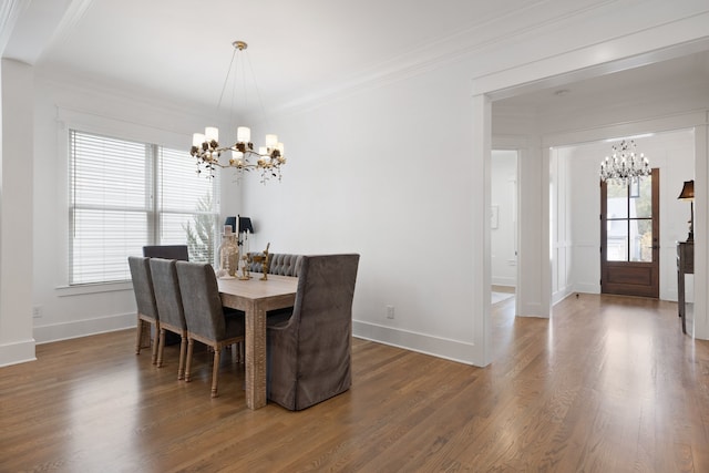 dining space featuring ornamental molding, wood-type flooring, and a notable chandelier