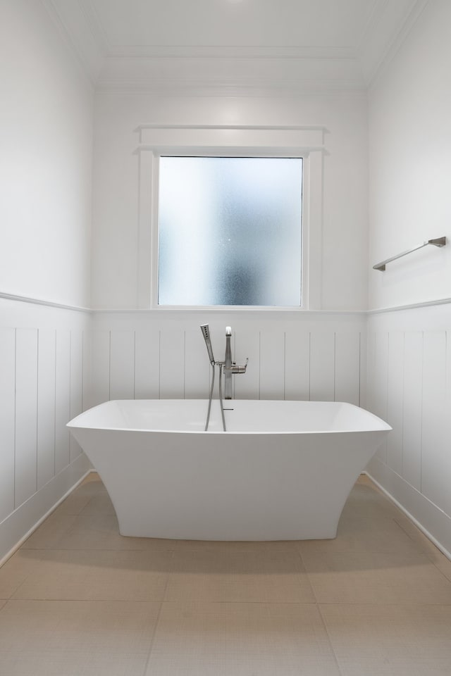 bathroom with tile patterned flooring, crown molding, and a bathing tub