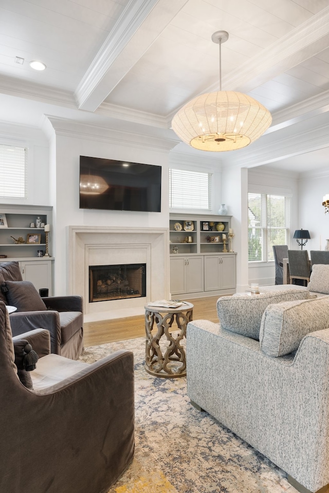 living room featuring ornamental molding, a fireplace, beam ceiling, an inviting chandelier, and hardwood / wood-style floors