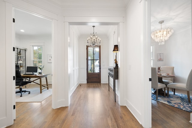 entryway featuring an inviting chandelier, hardwood / wood-style flooring, and crown molding