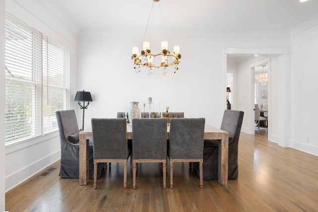 dining space with hardwood / wood-style floors, a notable chandelier, and ornamental molding