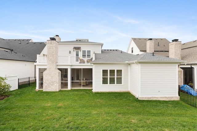 rear view of property with a balcony and a yard