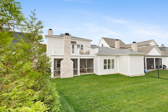 back of house with a sunroom, a lawn, and a balcony