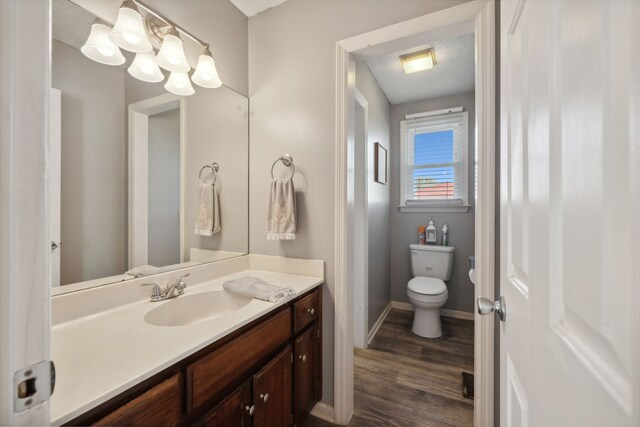 bathroom with toilet, vanity, a textured ceiling, and hardwood / wood-style flooring