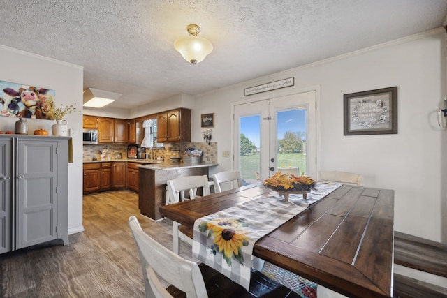 dining space featuring wood-type flooring, french doors, crown molding, a textured ceiling, and sink