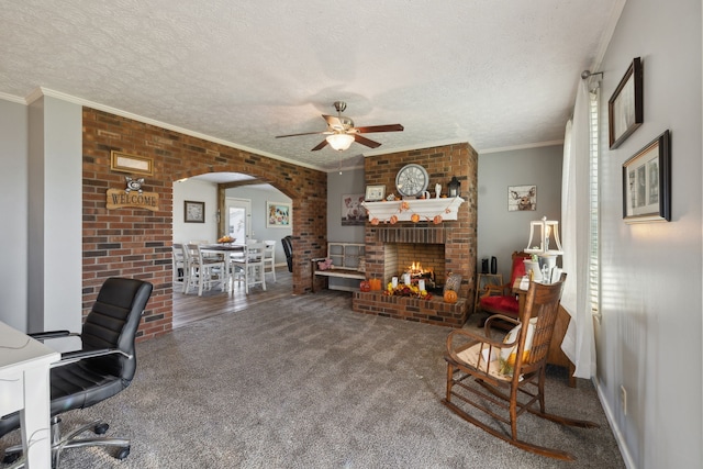 home office featuring carpet floors, ceiling fan, crown molding, and a brick fireplace