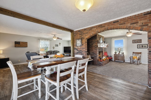 dining room with dark hardwood / wood-style flooring, brick wall, a textured ceiling, and a brick fireplace