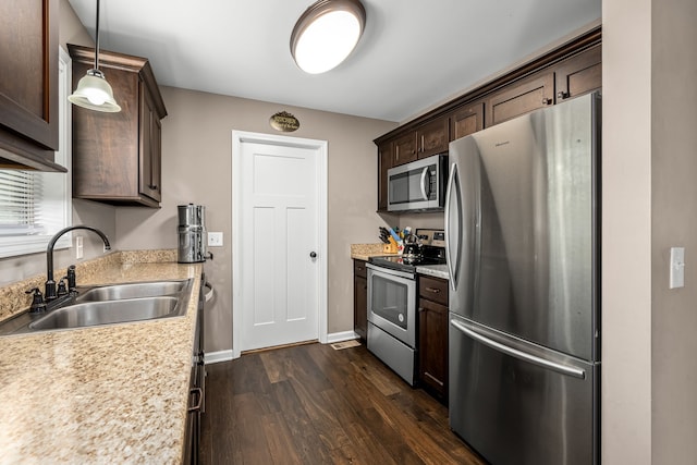 kitchen featuring stainless steel appliances, dark brown cabinets, dark hardwood / wood-style flooring, pendant lighting, and sink