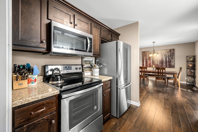 kitchen featuring light stone counters, appliances with stainless steel finishes, dark hardwood / wood-style floors, dark brown cabinets, and a chandelier