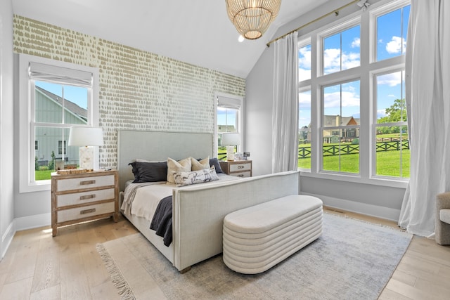 bedroom with an accent wall, light wood-type flooring, wallpapered walls, and baseboards