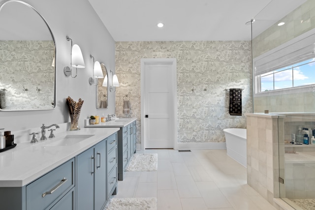 bathroom featuring a freestanding bath, a stall shower, a sink, and wallpapered walls