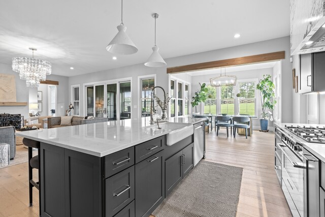 kitchen featuring decorative light fixtures, an inviting chandelier, appliances with stainless steel finishes, open floor plan, and a kitchen island with sink