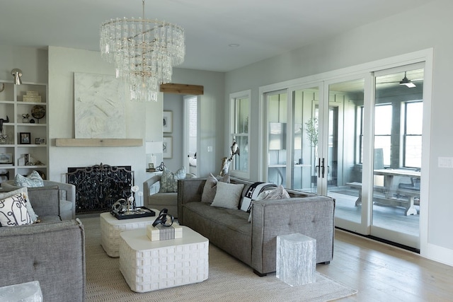 living room with a notable chandelier, french doors, a fireplace, and light wood-style floors