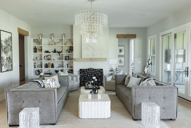 living area with light wood finished floors, a fireplace, and a notable chandelier