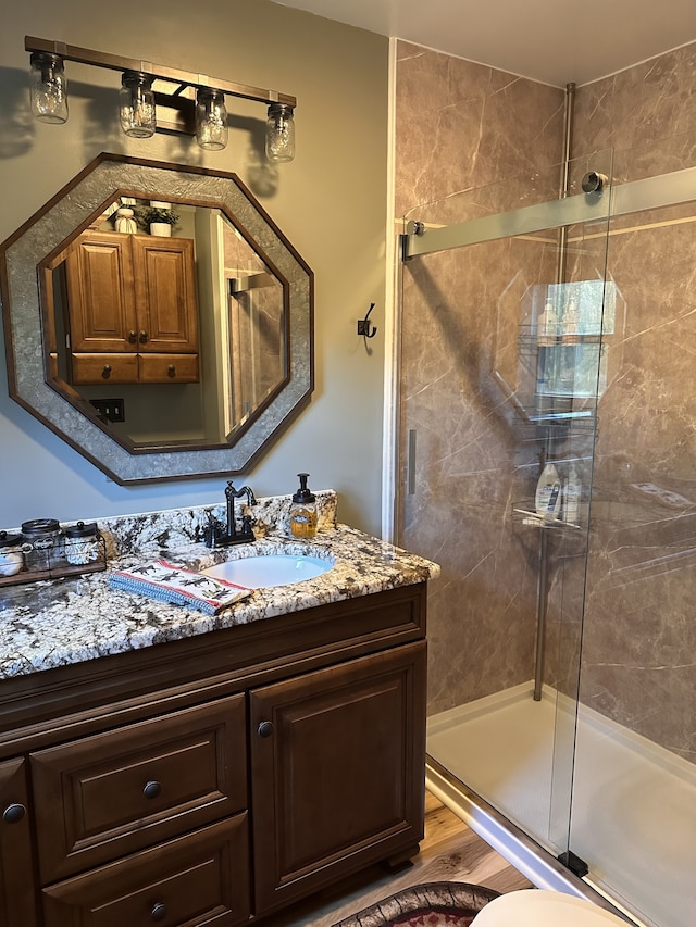 bathroom with toilet, vanity, hardwood / wood-style flooring, and a shower with shower door