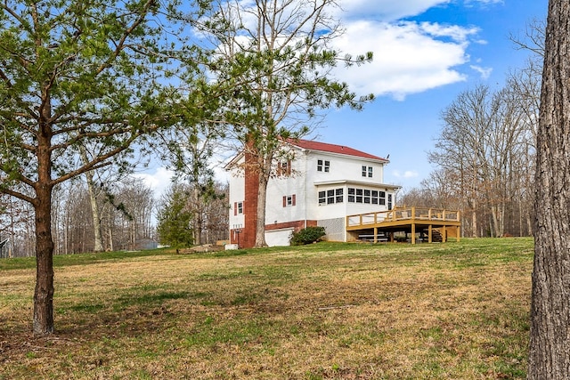 rear view of property featuring a wooden deck and a lawn