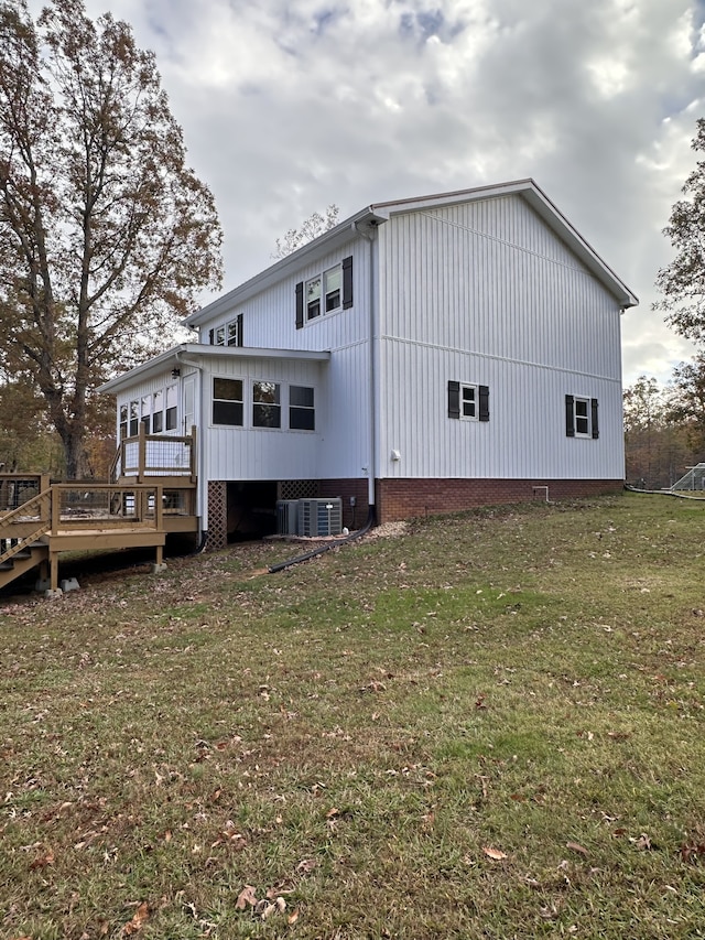 back of house with central AC unit, a lawn, and a wooden deck